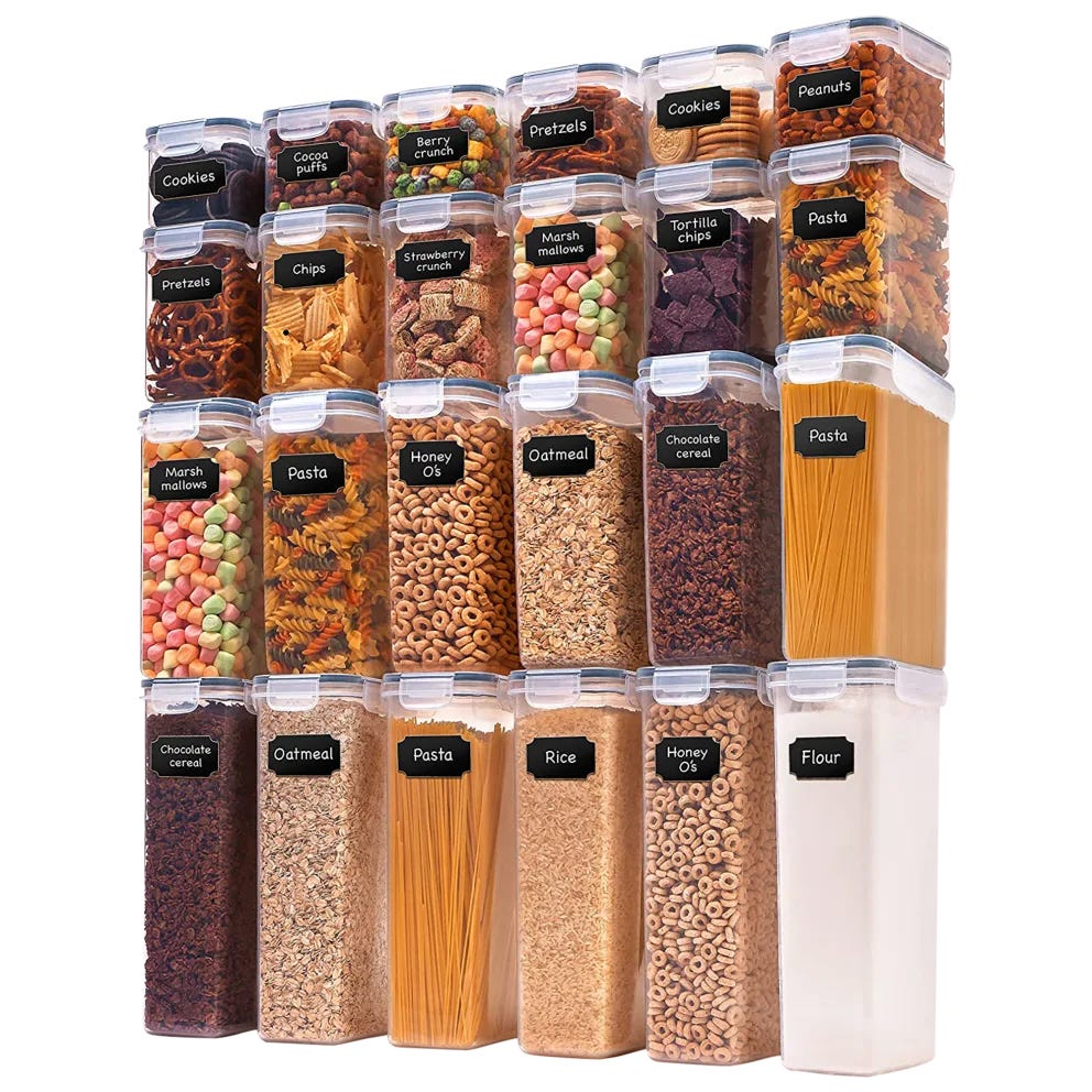 A collection of labeled clear storage containers hold various dry foods, including cookies, pretzels, chips, pasta, cereals, rice, flour, and marshmallows.