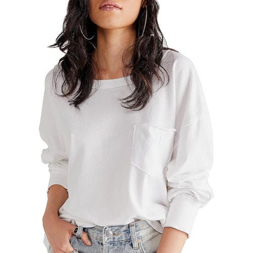 A woman wearing a white long-sleeve blouse with a chest pocket, paired with denim jeans.