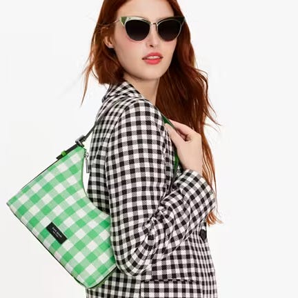 A woman wearing a checkered jacket and sunglasses carrying a green checkered shoulder bag.