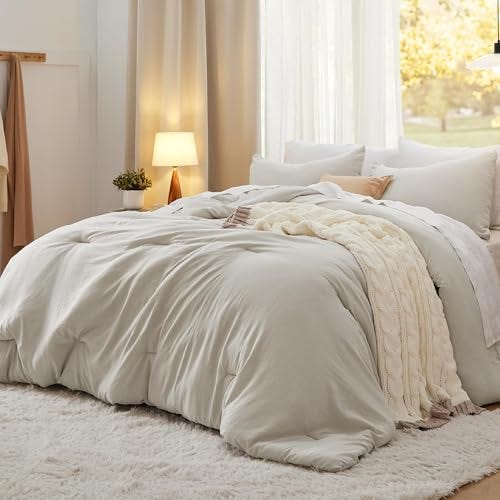 A soft-washed comforter set in a light cream color is displayed on a bed, with matching pillows arranged around it.