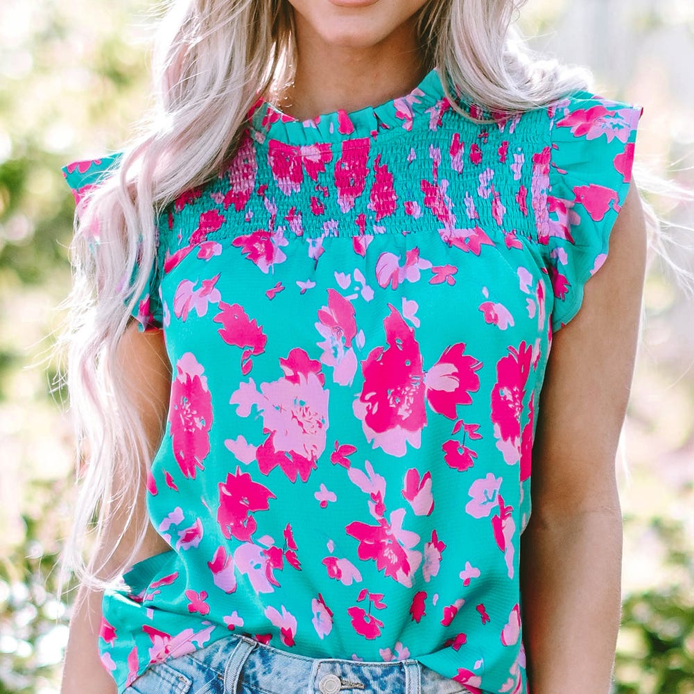 A woman wearing a bright turquoise top with pink floral print.