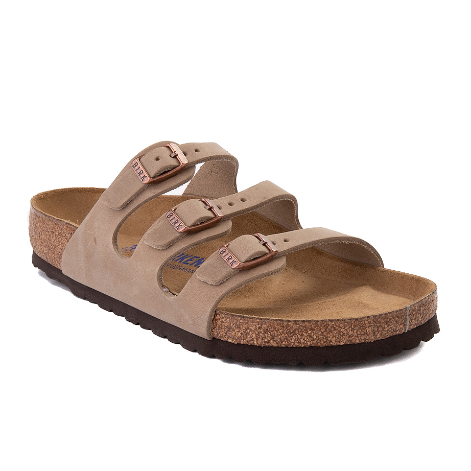 A pair of beige three-strap sandals with buckle closures and cork soles.
