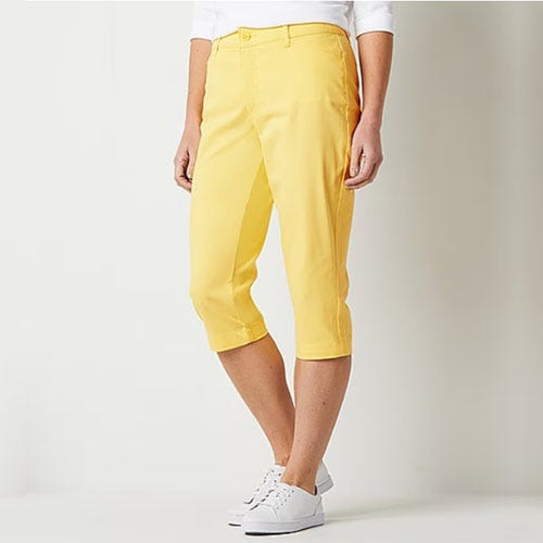 A pair of yellow capri pants and white sneakers worn by a model.