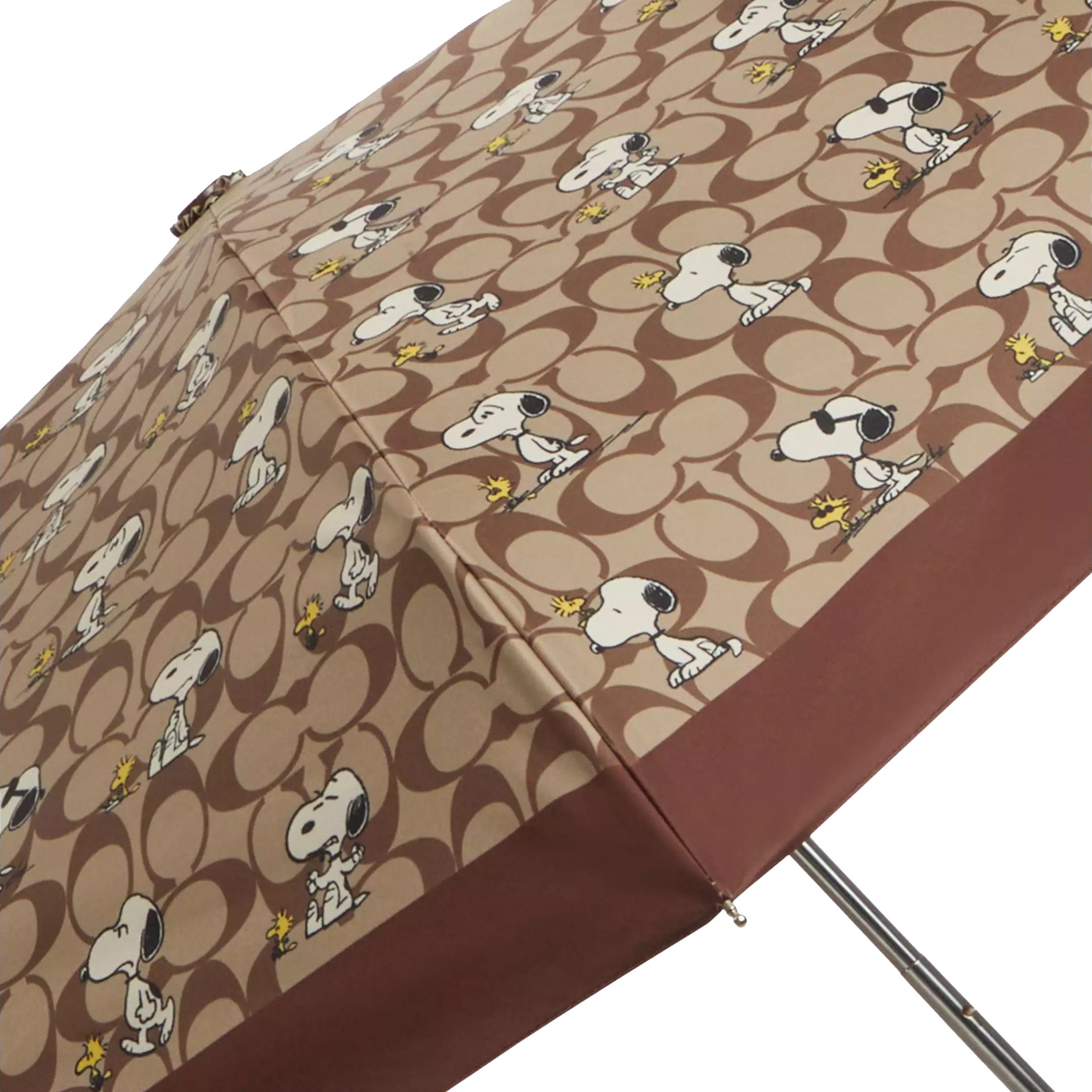 A brown umbrella featuring a repeating pattern of Snoopy and Woodstock characters on a circular background.