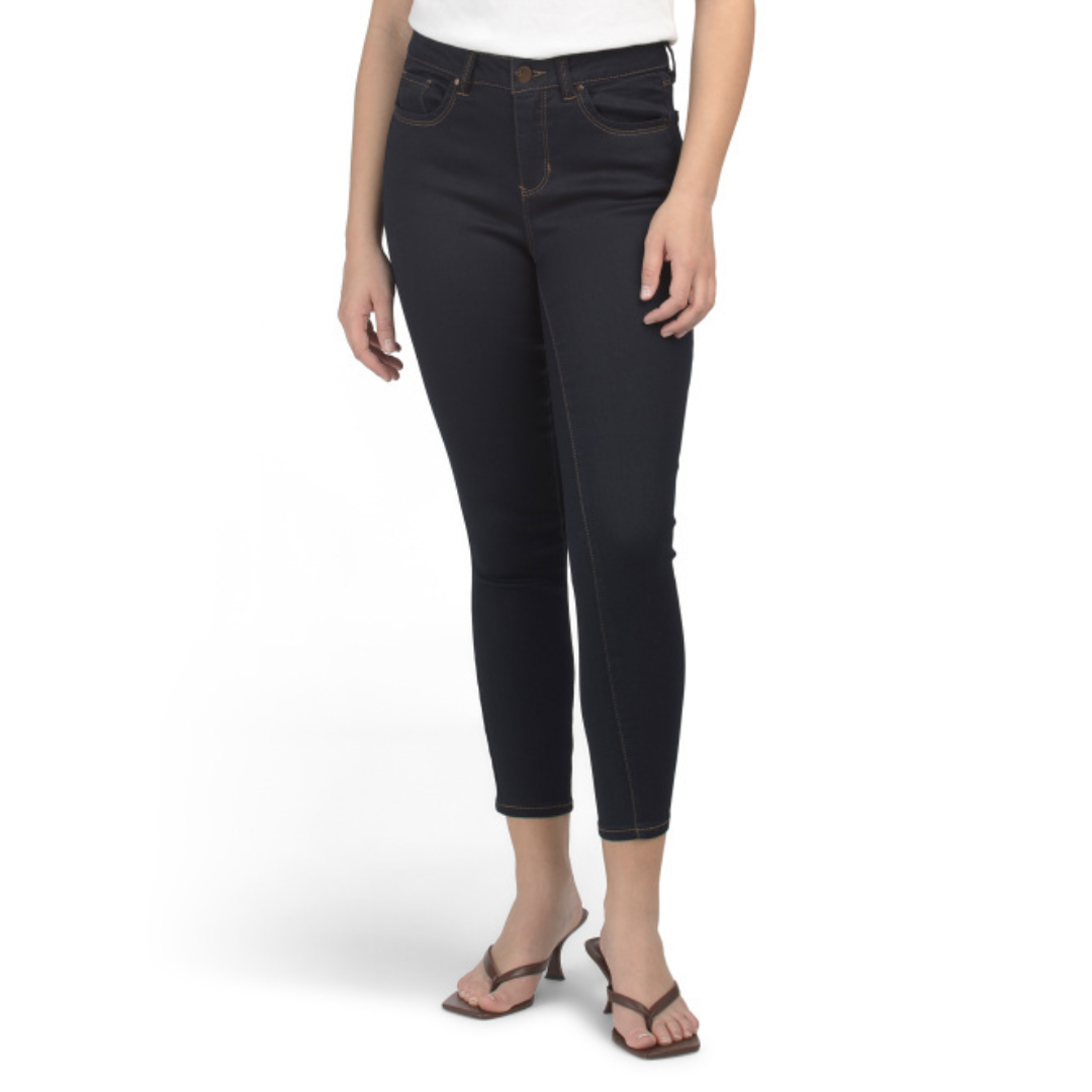 A person is wearing dark skinny jeans with orange stitching and black heeled sandals.