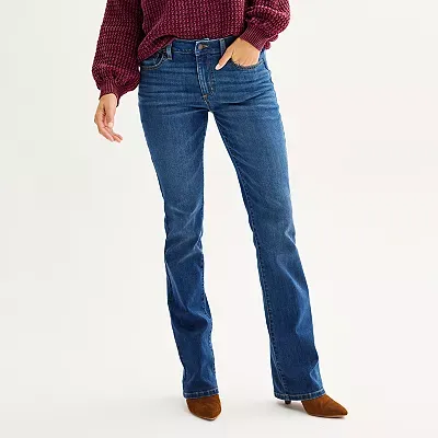 A person is wearing mid-rise bootcut jeans in a medium blue wash, designed with a classic five-pocket style and belt loops, paired with brown boots.