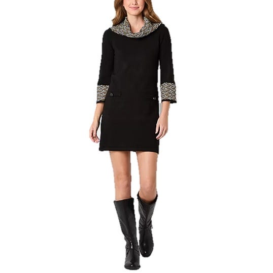 A woman wears a black dress with patterned cuffs and a cowl neck, paired with knee-high black boots.