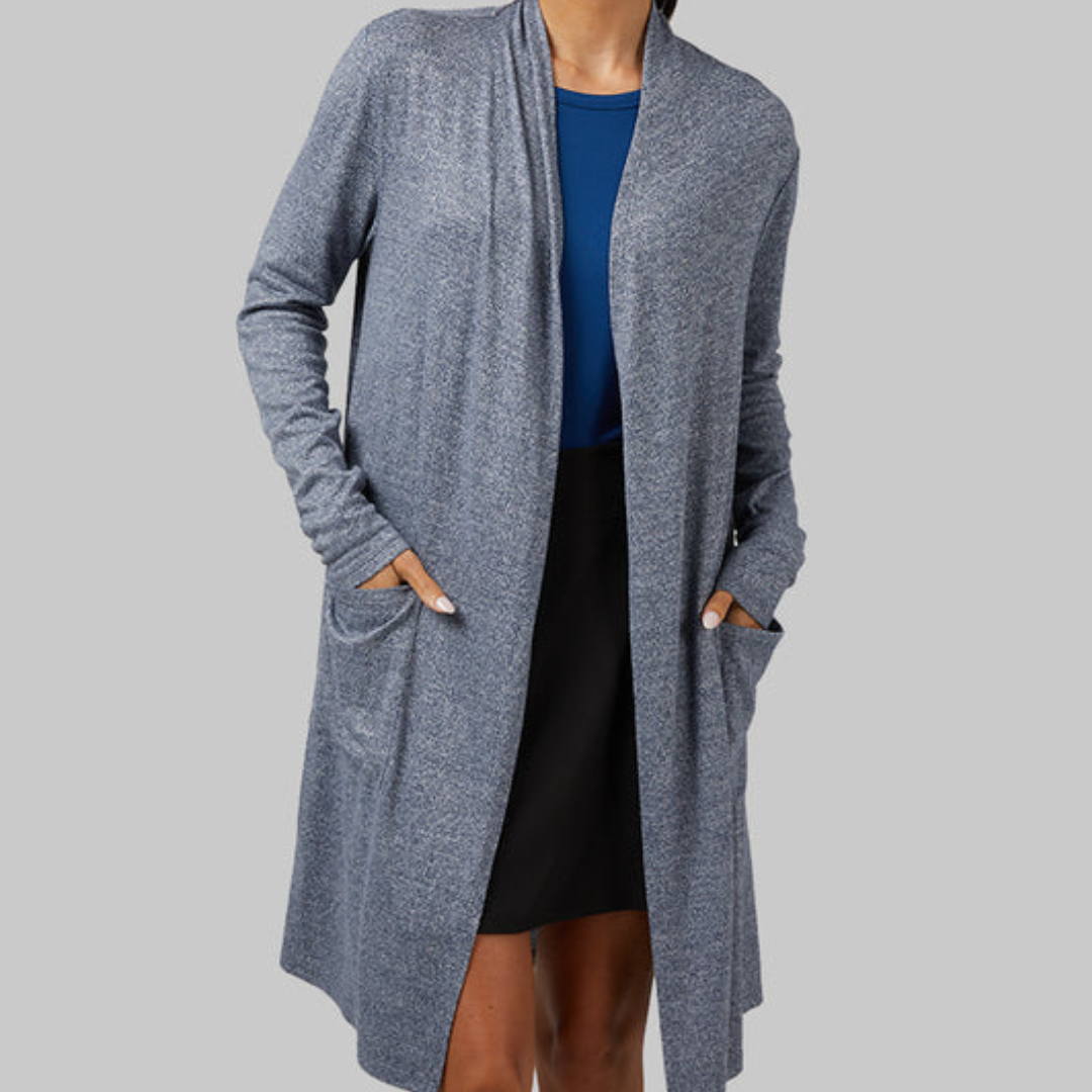 A woman wearing a long sleeve, gray cardigan over a blue top and a black skirt.