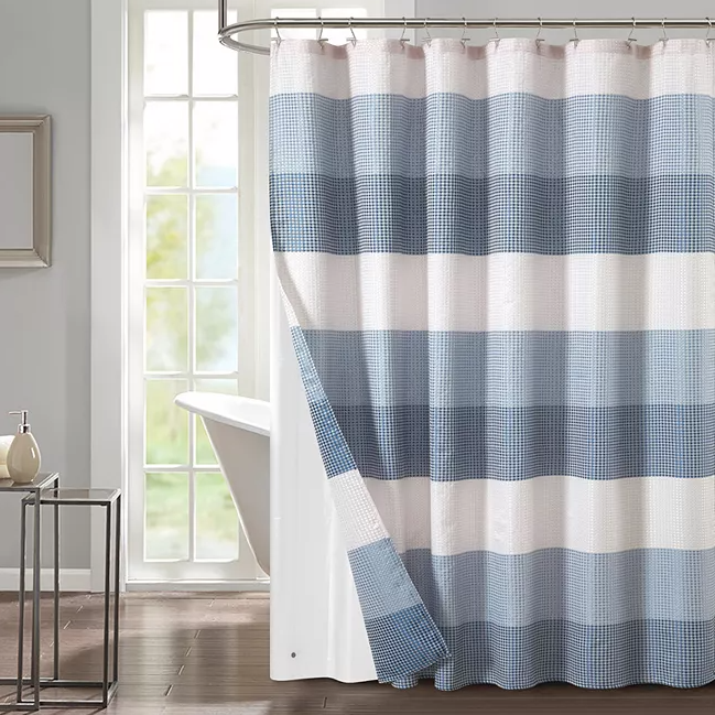 Blue and white striped shower curtain with a gingham pattern, displayed in a bathroom setting.