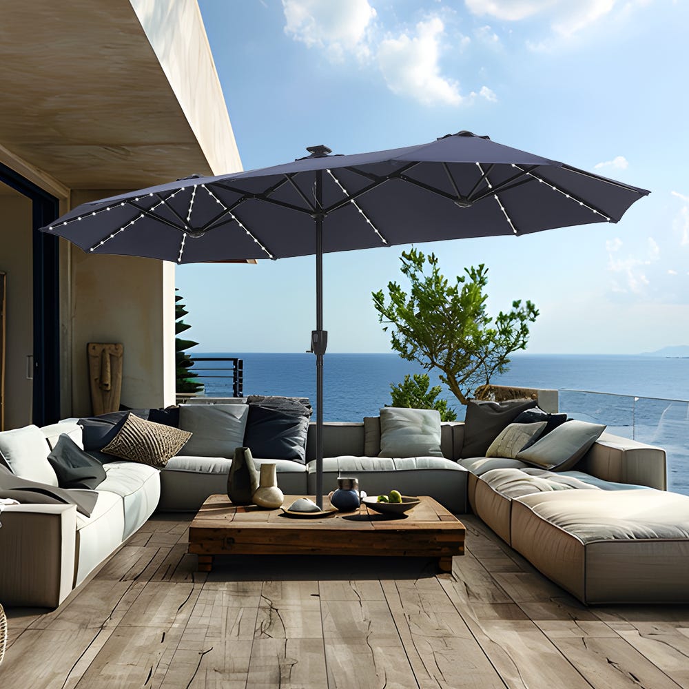 An outdoor patio scene with a large umbrella, modular sofa set, wooden coffee table, and ocean view.