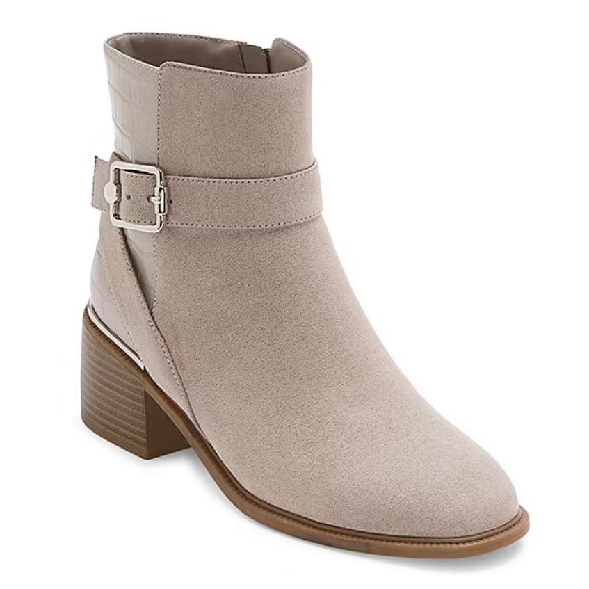 A beige ankle boot with a strap and buckle detail and a block heel.