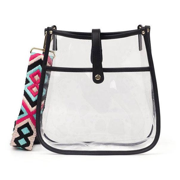 A clear PVC shoulder bag with black trim features a colorful, wide woven strap with geometric patterns in pink, blue, and black. It has a simple snap closure at the top.