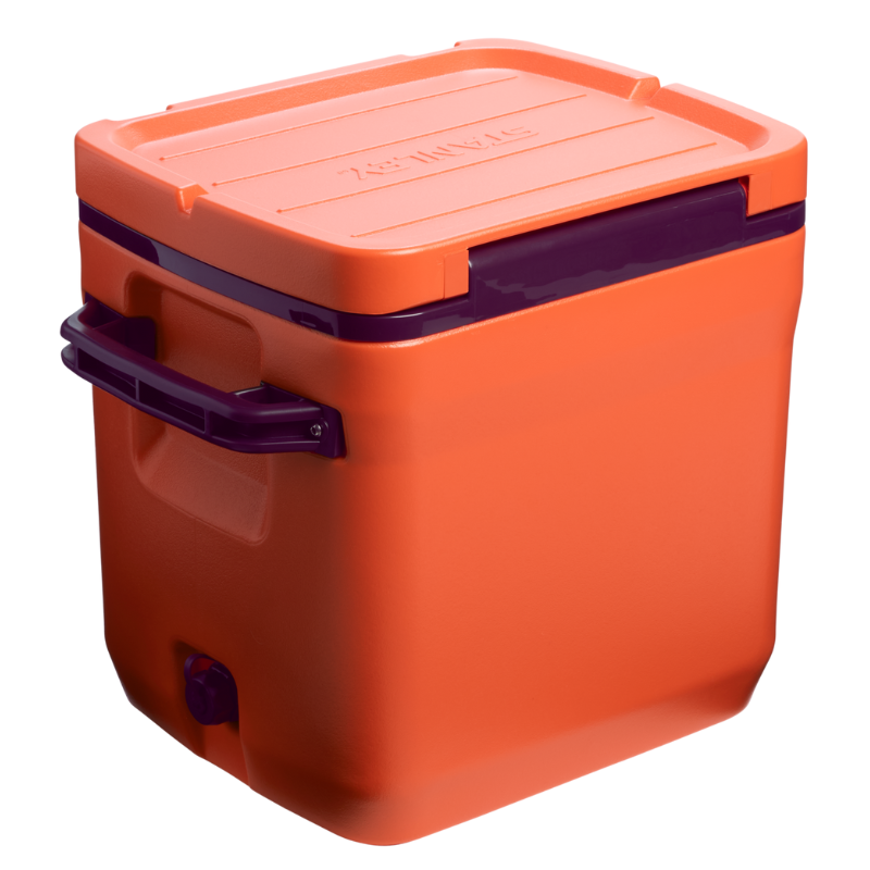 An orange outdoor cooler with a purple handle and lid, featuring a secure latch and a drainage spout at the bottom.