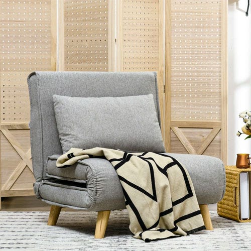 A grey accent chair with a cushion and a cream-and-black throw blanket draped over one corner, positioned in front of a wooden folding screen.