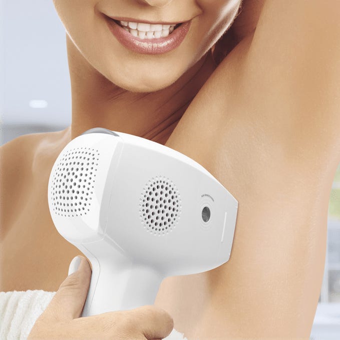 A handheld garment steamer held by a smiling person.