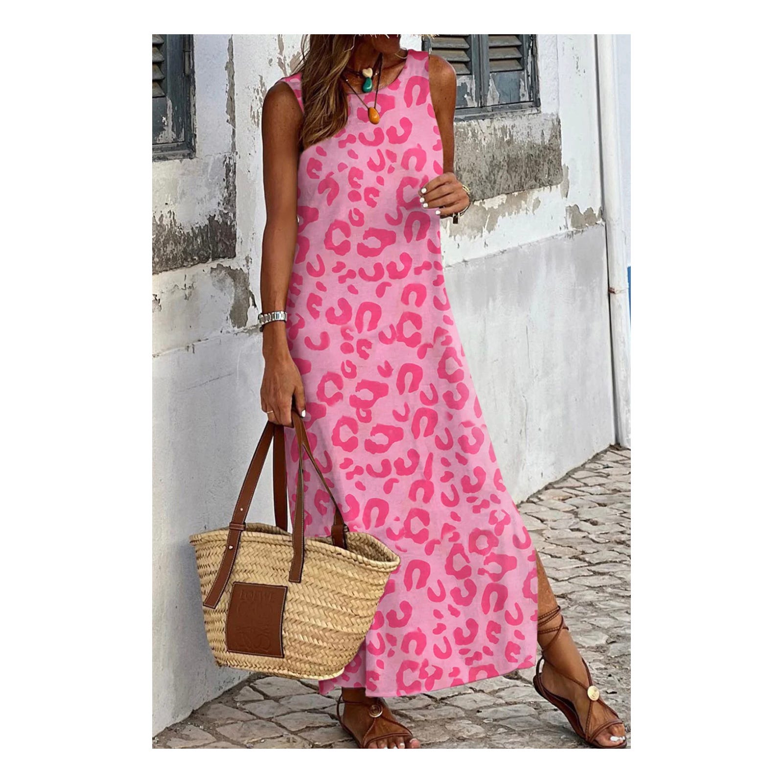 A woman wears a pink sleeveless dress with leopard print, holding a woven tote bag and wearing brown sandals.