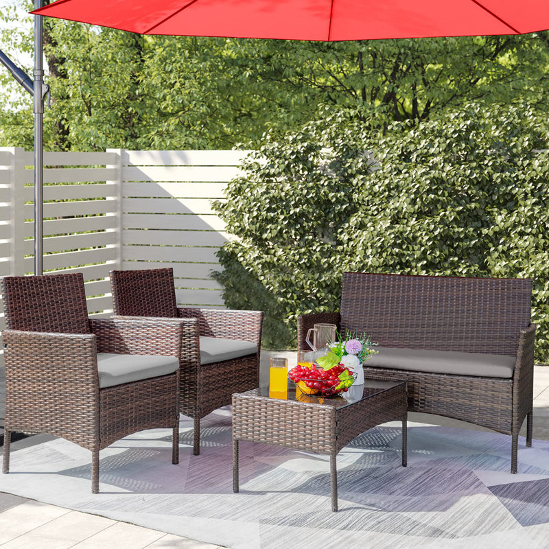 Rattan-style garden furniture set with a two-seater sofa, two chairs, a table, and an umbrella.