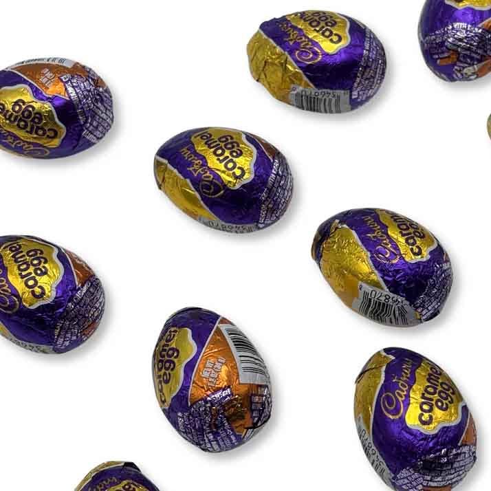 A collection of Cadbury Caramel Eggs wrapped in purple and gold foil, showcasing the well-known brand logo.