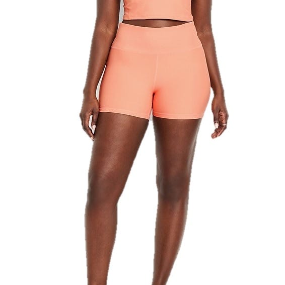 A person is wearing high-waisted peach-colored athletic shorts, paired with a matching cropped top.