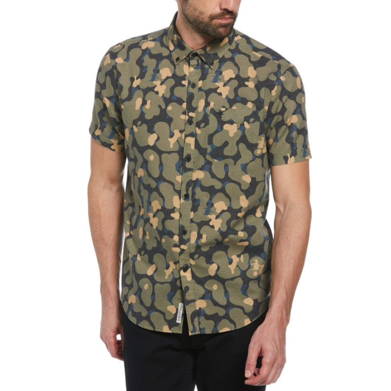 A man wears a short-sleeve button-up shirt with a green, brown, and black camouflage pattern.