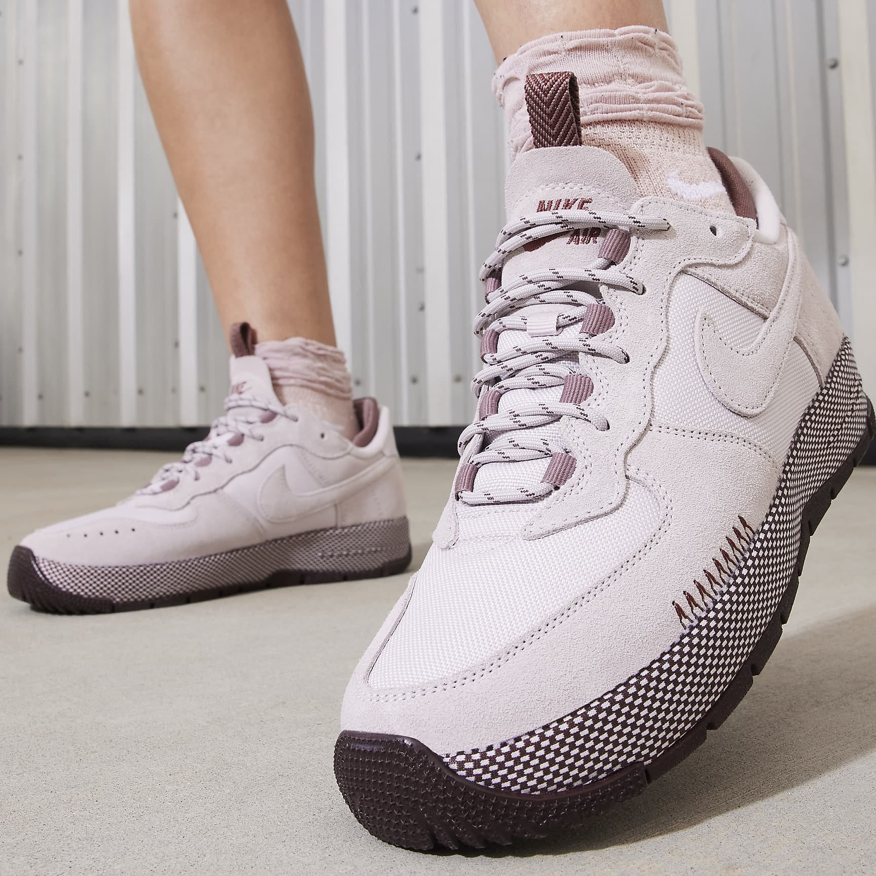A pair of pale pink sneakers with dark brown soles and accents.