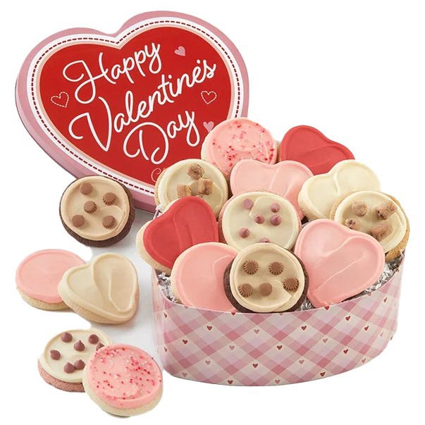 A heart-shaped tin with 16 cookies featuring Valentine's Day-themed decorations, including heart and round shapes, with pink, red, and white icing, some topped with chocolate chips and sprinkles. The tin has a \“Happy Valentine's Day\“ message on the lid.