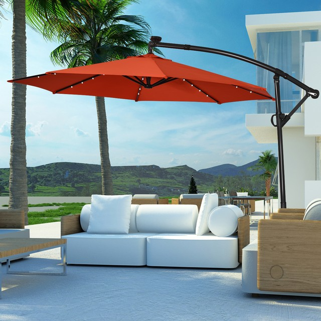Outdoor setting with a large red cantilever umbrella and modern white modular sofas.