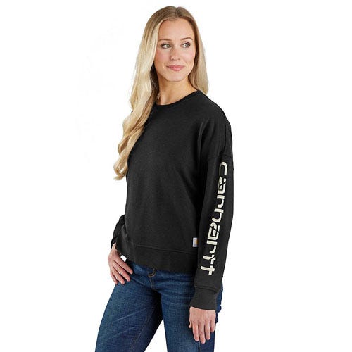 A woman wears a black Carhartt sweatshirt with the brand's name vertically on the sleeve, paired with blue jeans.