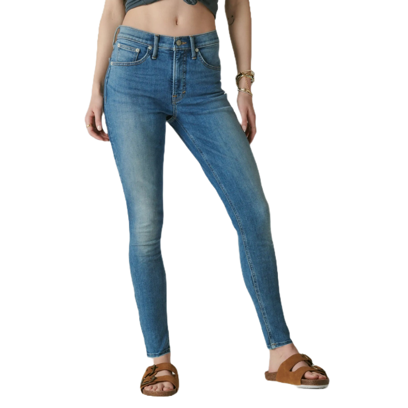 High Rise Bridgette Skinny Jeans feature a fitted silhouette with a high waist and a classic blue denim wash. They are paired with brown open-toe sandals.