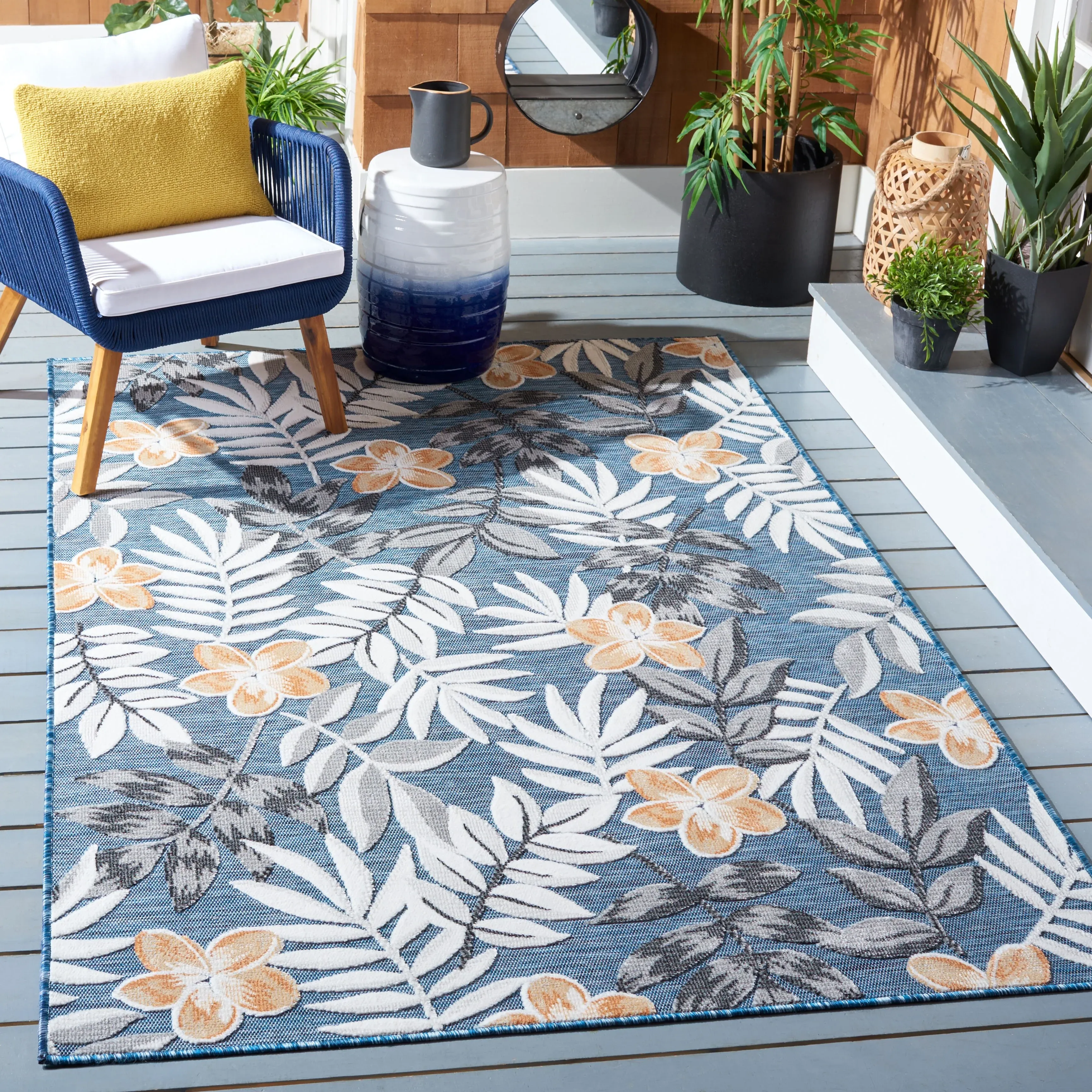 Safavieh 4' x 6' rug with a blue background, featuring a floral pattern of white and orange flowers and grey leaves, perfectly accentuating modern or outdoor decor spaces.