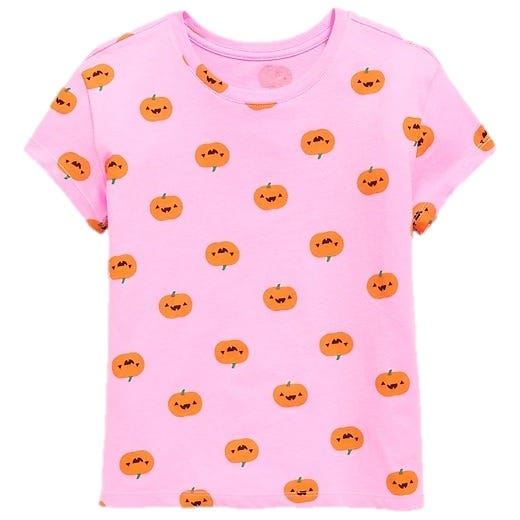 A pink T-shirt featuring a pattern of small, smiling orange pumpkins.