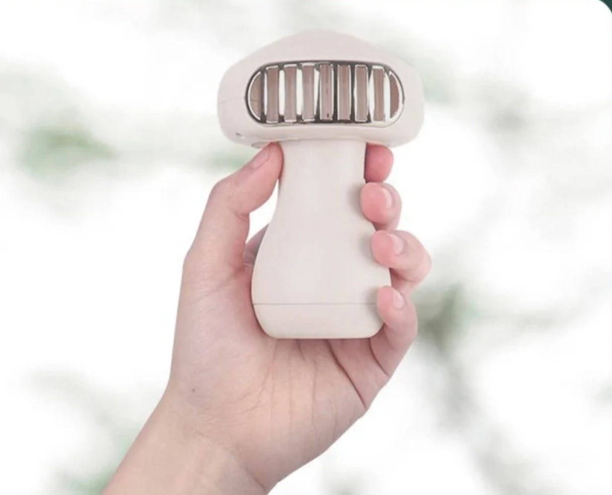 A hand-held fabric shaver with a white grip and a beige head.