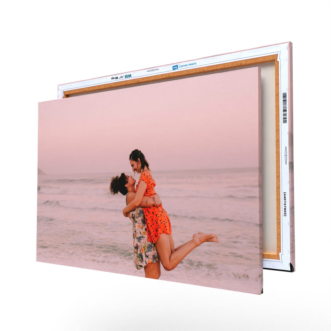 The photo shows a canvas print of two people embracing on a beach, with packaging visible on the side.