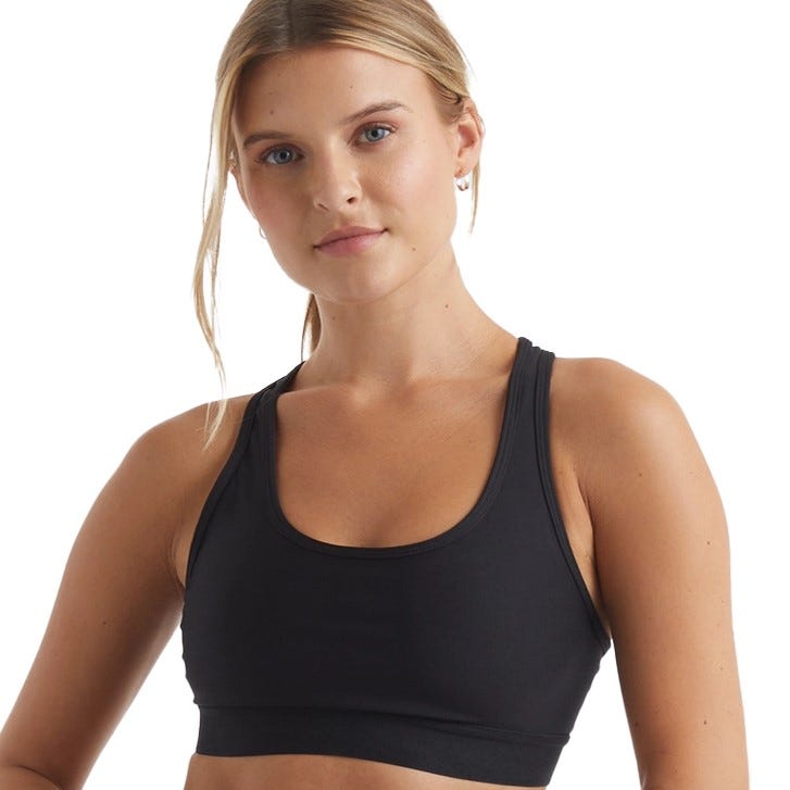 A woman wearing a black sports bra with a scoop neckline and racerback straps.