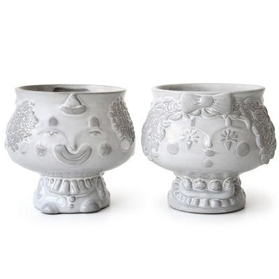 Two white ceramic vases with raised clown face designs, each showcasing different expressions and ornate details.