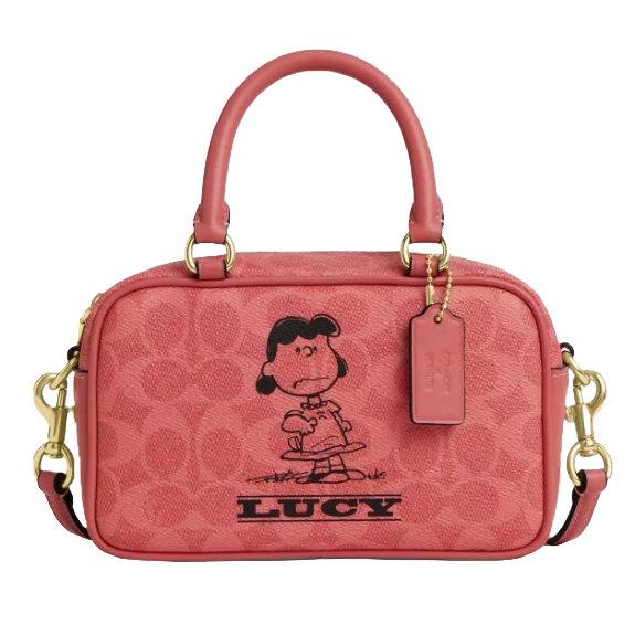 A pink handbag featuring a graphic of a cartoon character named Lucy. It has two handles, a detachable shoulder strap, gold-tone hardware, and a tag.