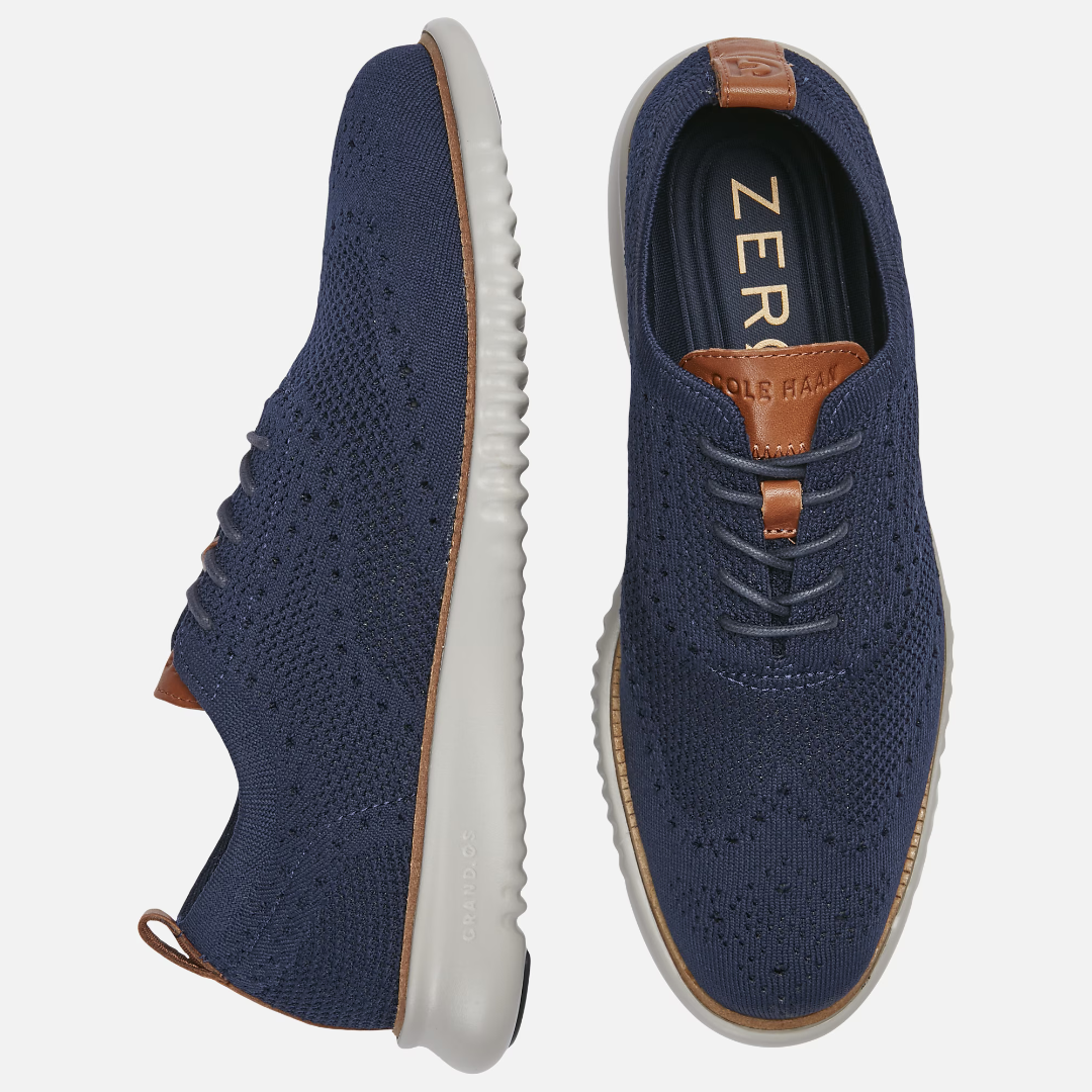 A pair of navy blue sneakers with white soles and brown leather accents on top and back.