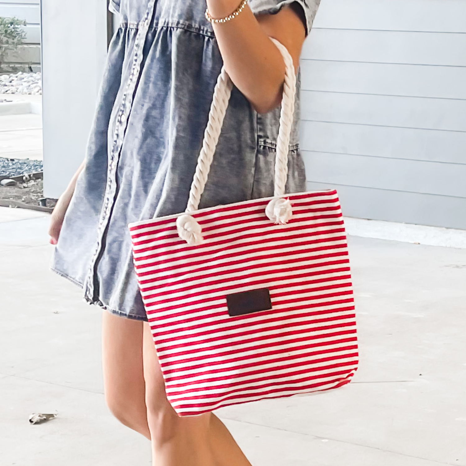A red and white striped canvas tote with rope handles, featuring a small black rectangular patch on the front.