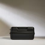 Black hard-shell suitcase with horizontal stripes design and a retractable handle on top.