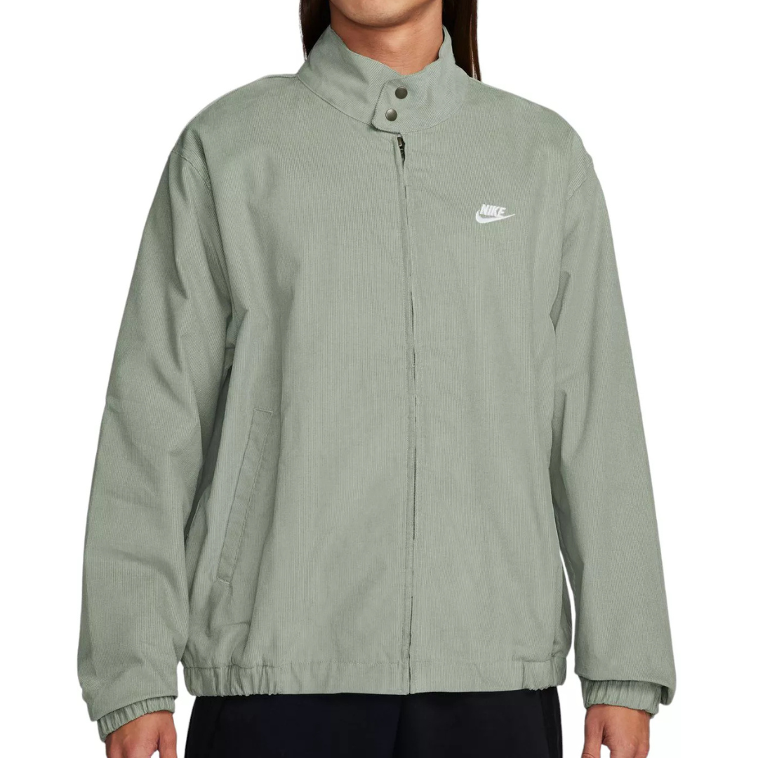 A light green Nike jacket with a high collar, snap buttons, and zip closure, featuring the Nike logo on the chest and side pockets.