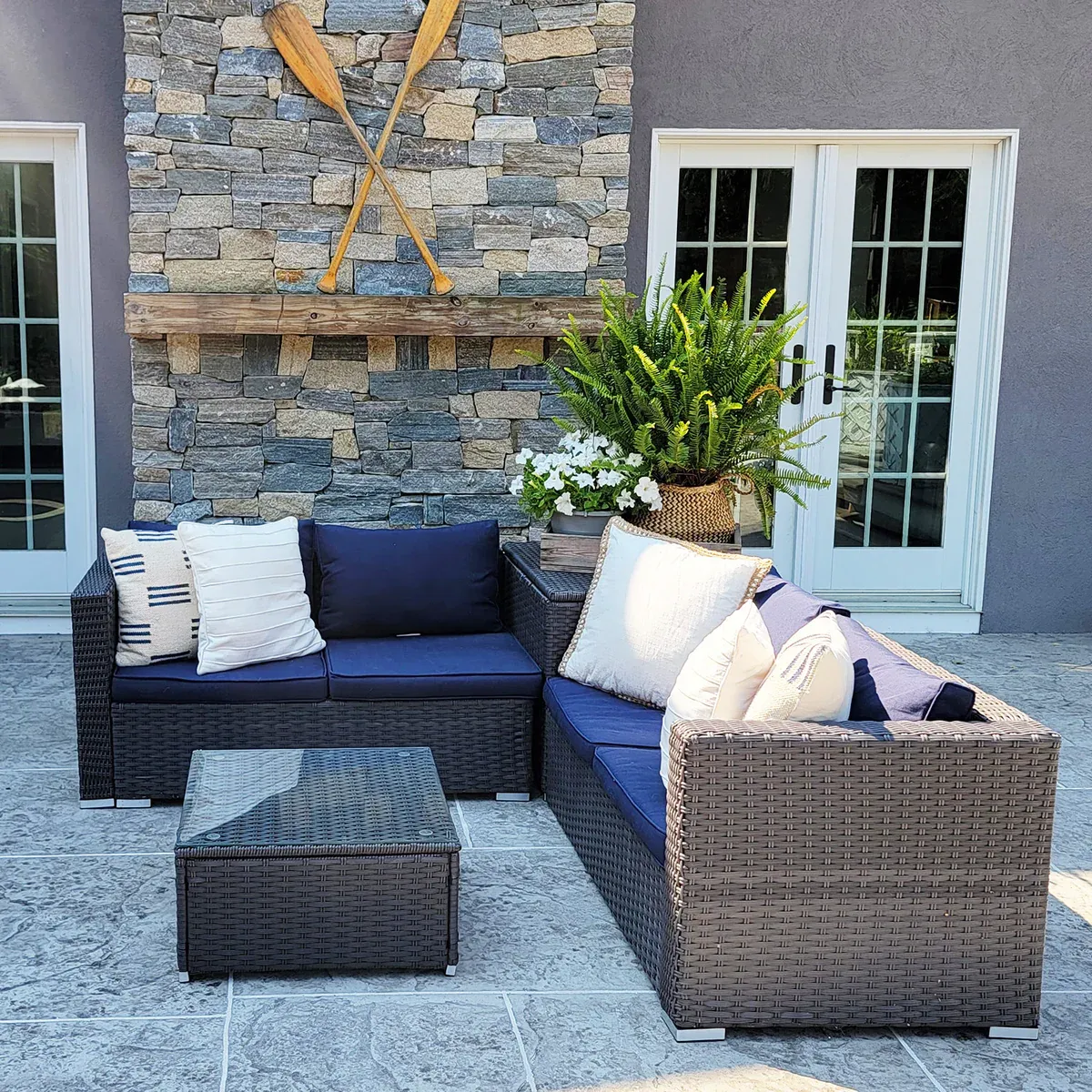 A four-piece patio set with dark wicker design consists of a loveseat, two armchairs, and a matching wicker storage table with a glass top.