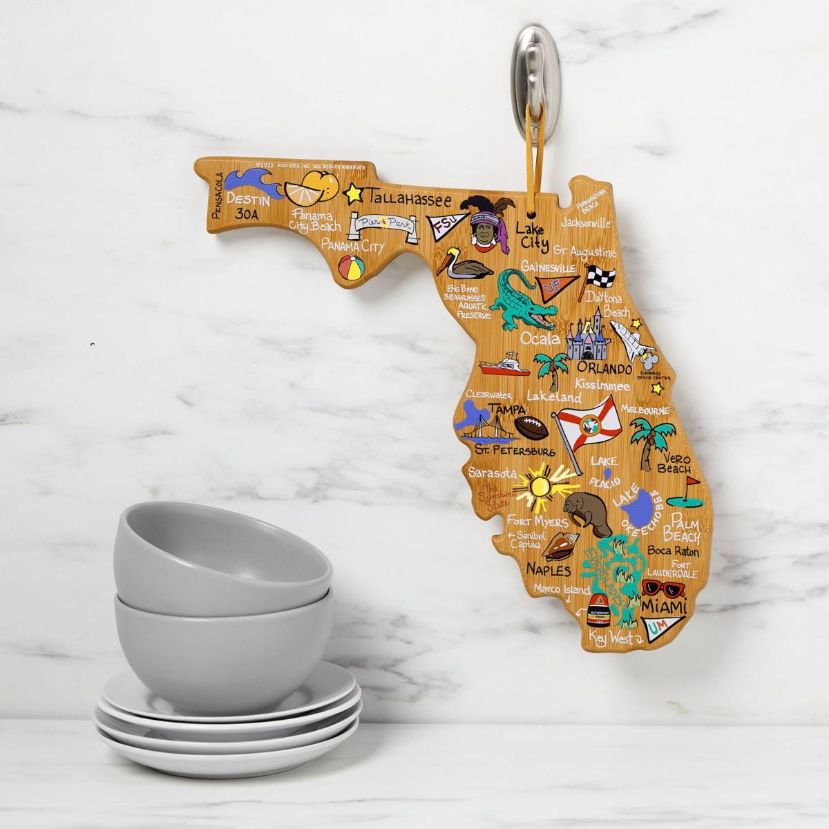 A Florida-shaped souvenir key holder with colorful illustrations and a set of four stacked gray bowls on white saucers.