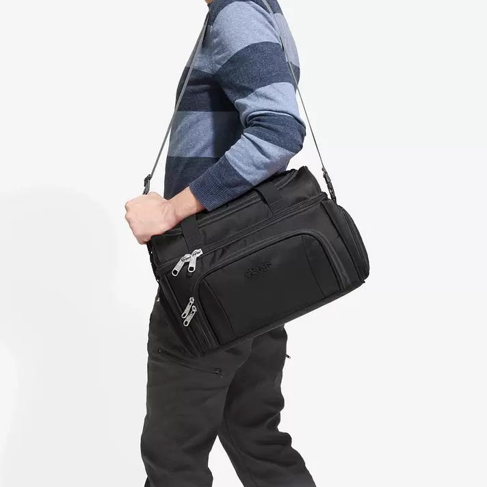 A person is carrying a black shoulder messenger bag with multiple zip compartments.