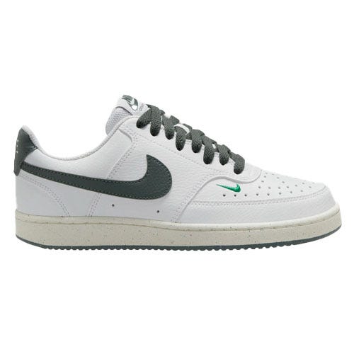 White low-top sneaker with a dark green swoosh, perforated toe box, dark green laces, and a small green logo near the sole.