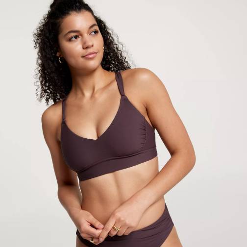 A woman is wearing a brown sports bra and matching leggings.