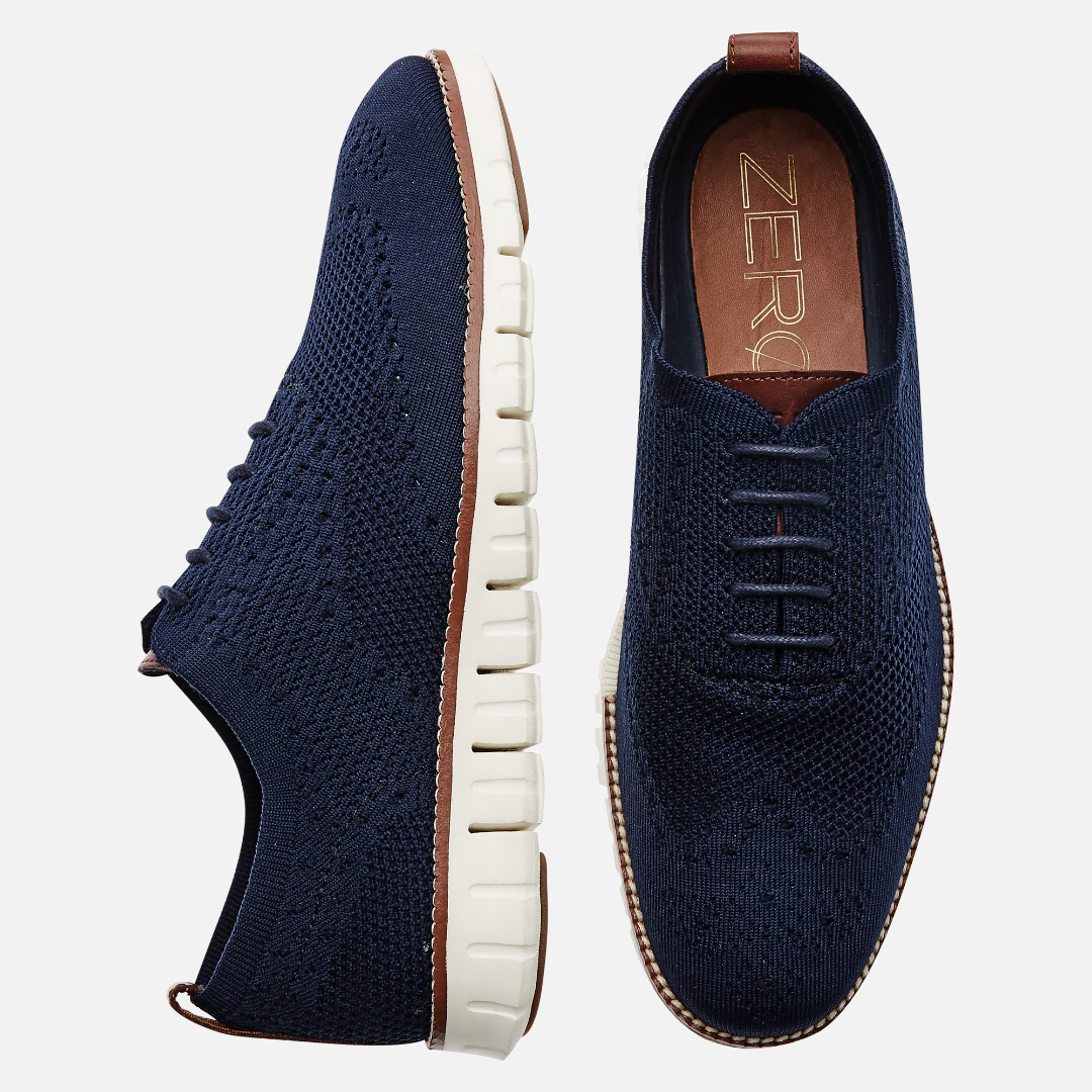 A pair of navy blue knit sneakers with white soles and leather details.