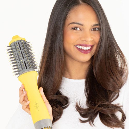 A woman holding a yellow hair styling brush.