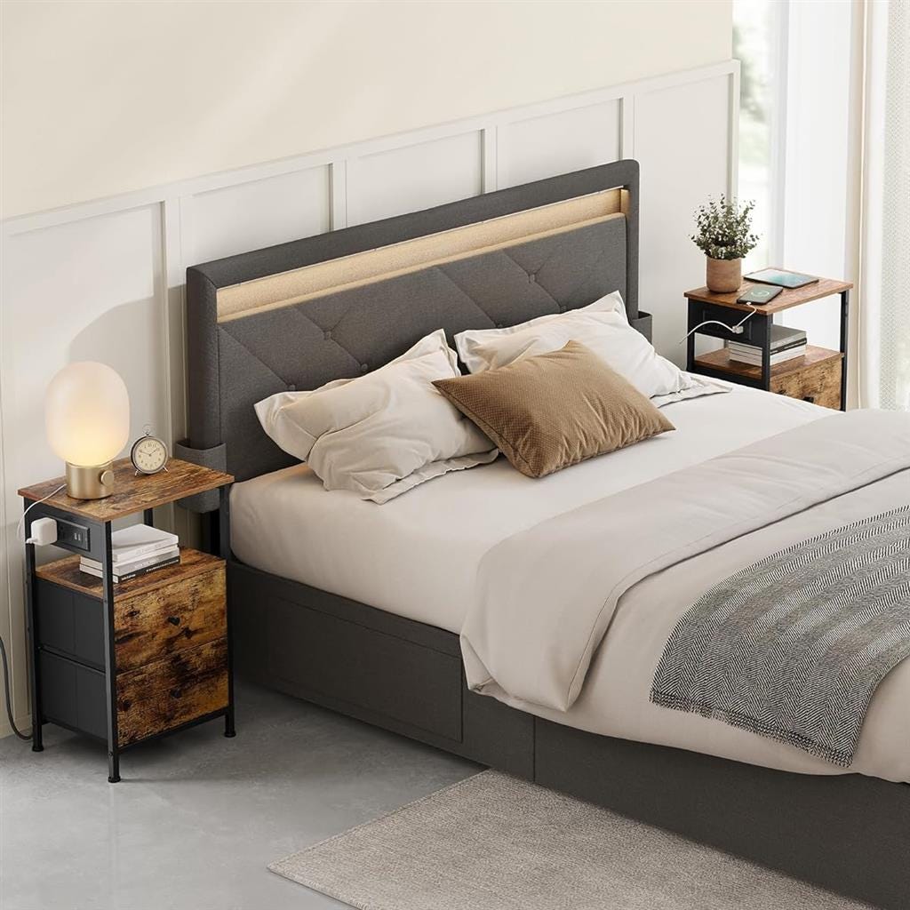 A bedroom scene with a bed that has a gray upholstered headboard, white bedding with beige accents, two nightstands, a glass lamp, clock, and decor.
