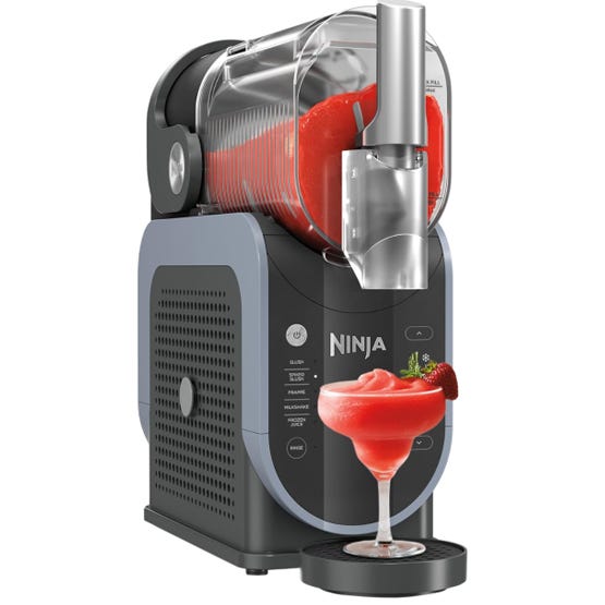 A Ninja drink system dispenses a red frozen beverage into a glass with a strawberry garnish.
