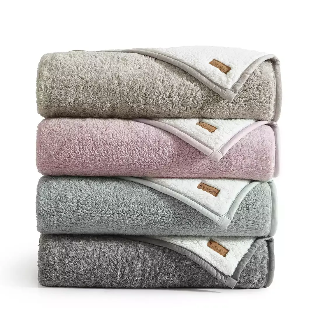 Stacked plush towels in gray, pink, and white hues.